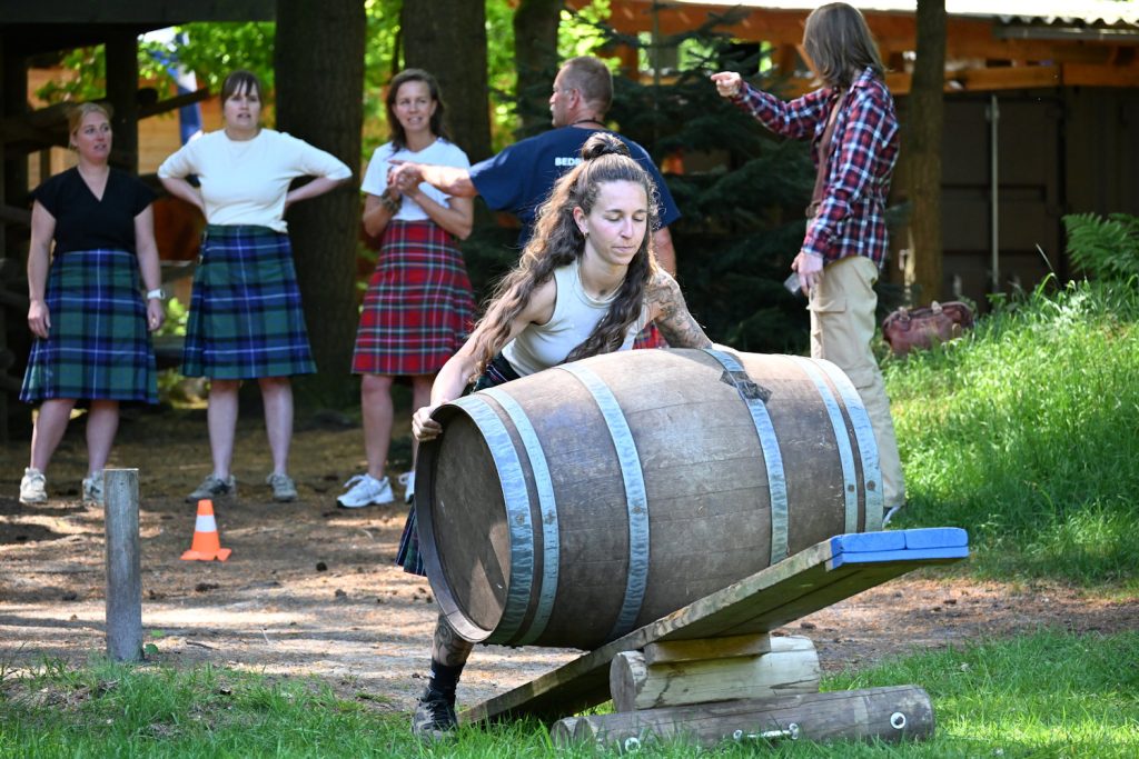 Deelneemster in kilt rolt een houten vat tijdens de Highland Games